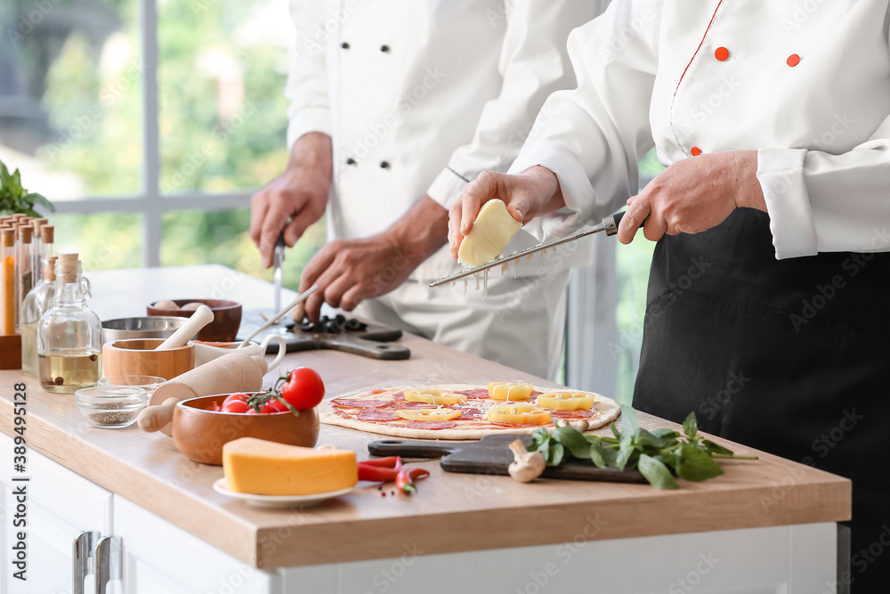 Chefs cooking tasty pizza in kitchen