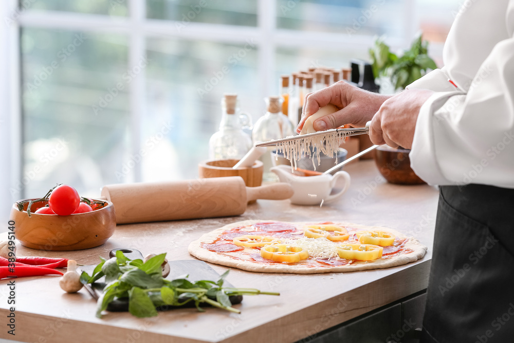 Chef making tasty pizza in kitchen