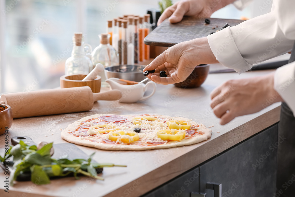 Chefs cooking tasty pizza in kitchen