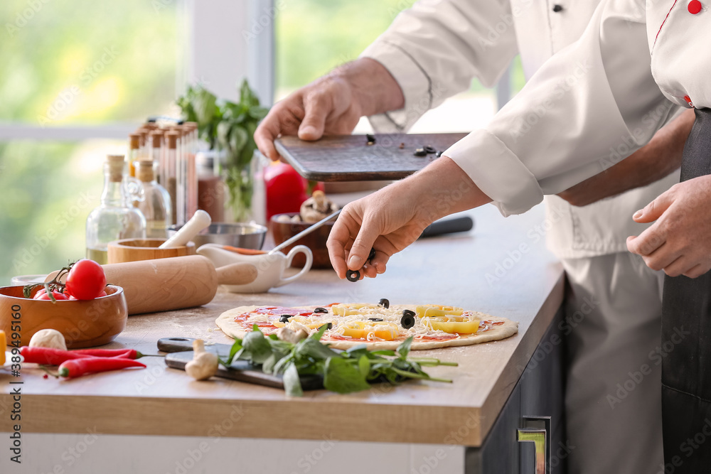 Chefs cooking tasty pizza in kitchen