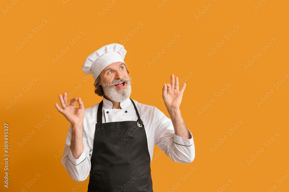 Mature male chef showing OK on color background