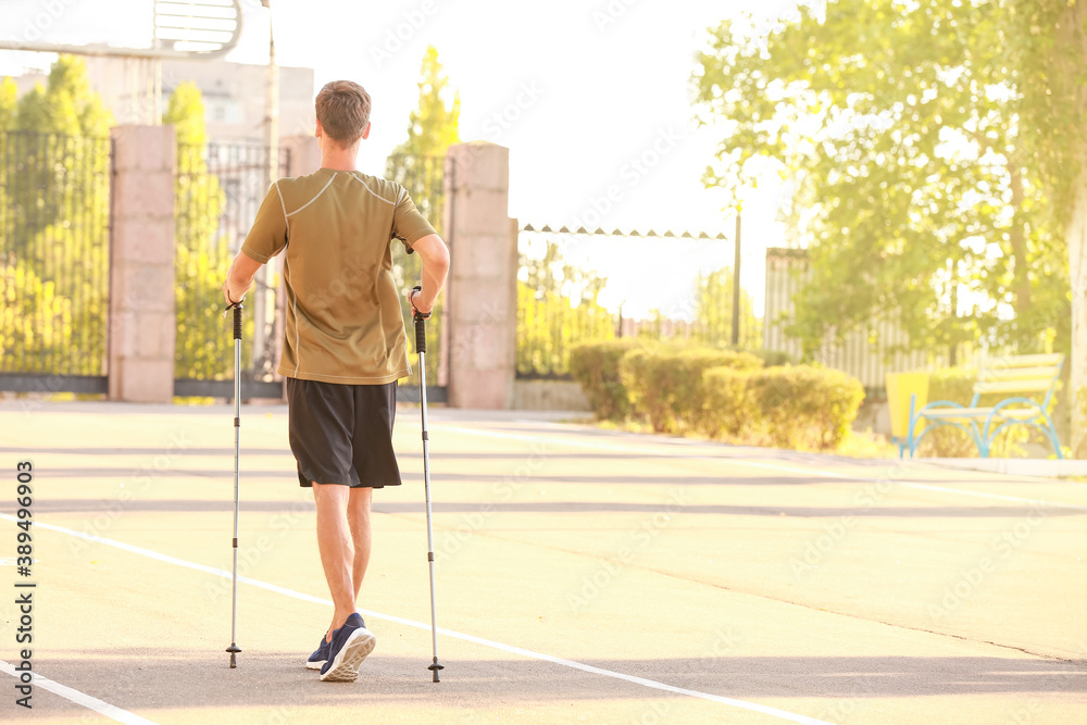 Young man training with walking poles outdoors