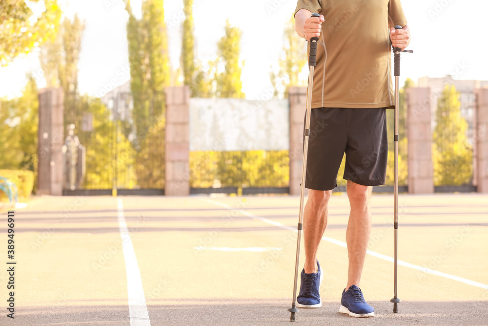 Young man training with walking poles outdoors