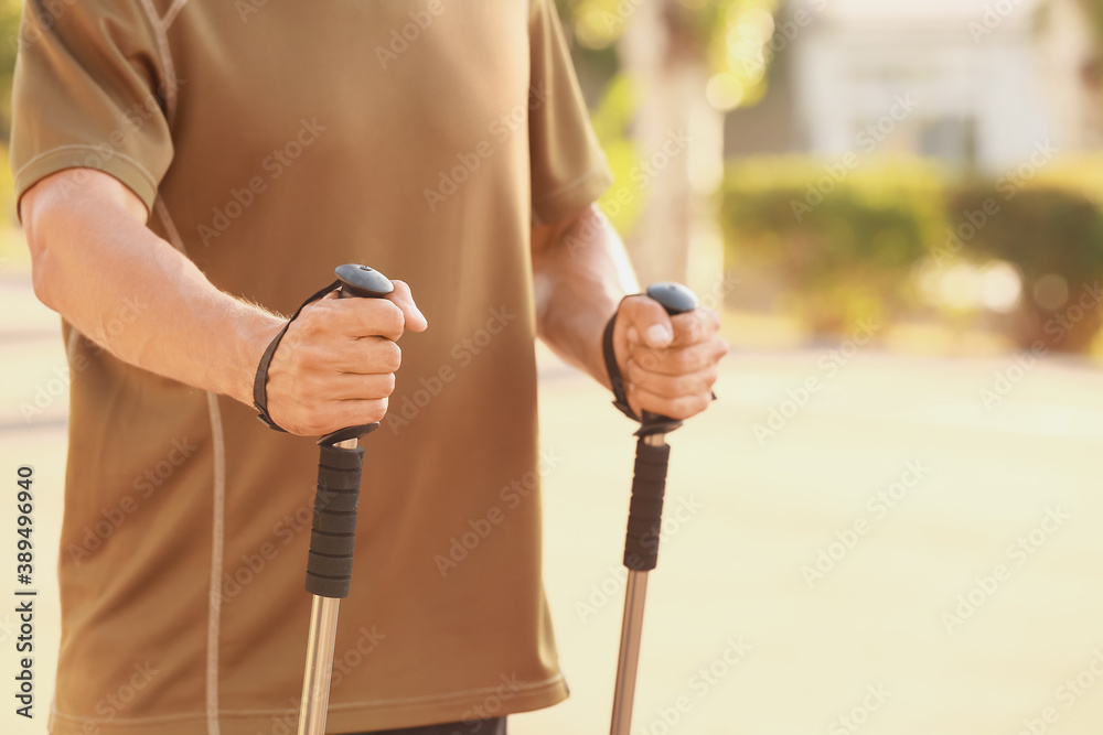 Young man training with walking poles outdoors