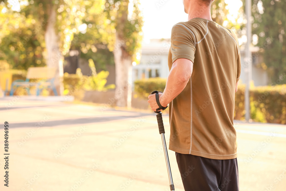 Young man training with walking poles outdoors