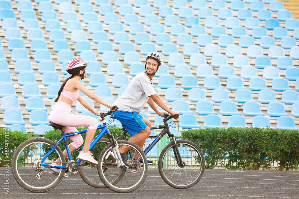 Sporty young couple riding bicycles at the stadium