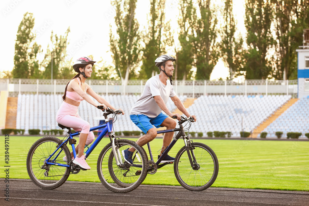 Sporty young couple riding bicycles at the stadium