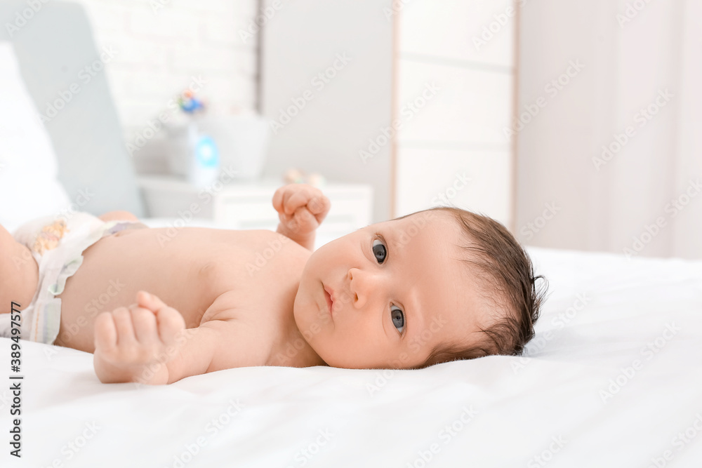 Cute little baby lying on bed at home