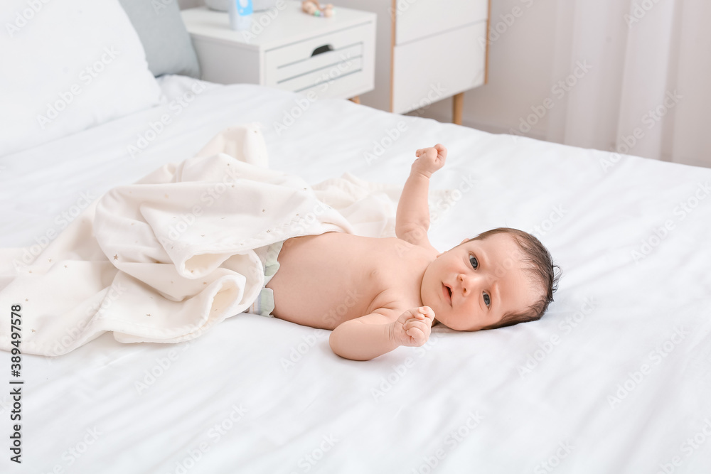 Cute little baby lying on bed at home