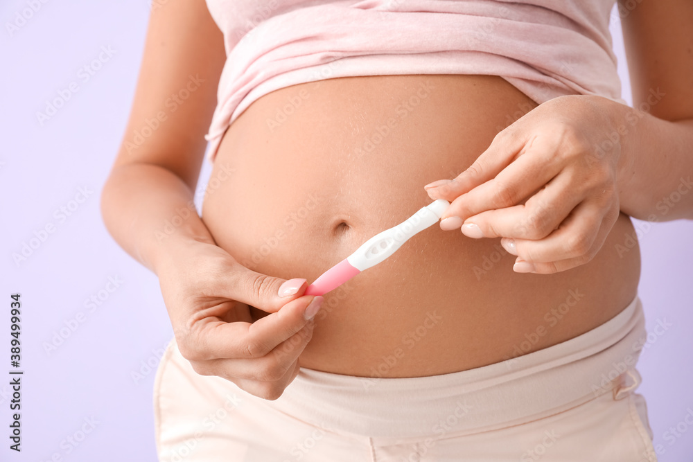 Beautiful pregnant woman with test on color background