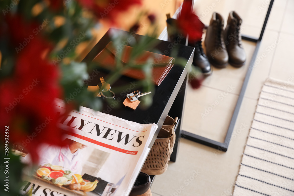 Keys with wallet and newspaper on stand in hall