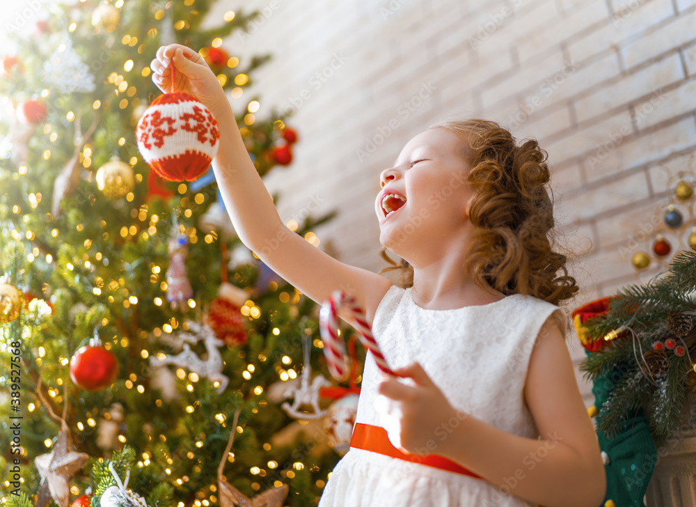 girl is decorating Christmas tree