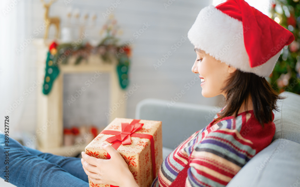 woman with present near Christmas tree indoors.