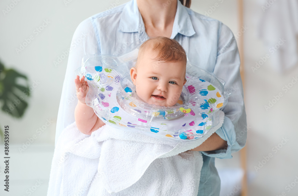 Woman and cute baby with inflatable ring at home