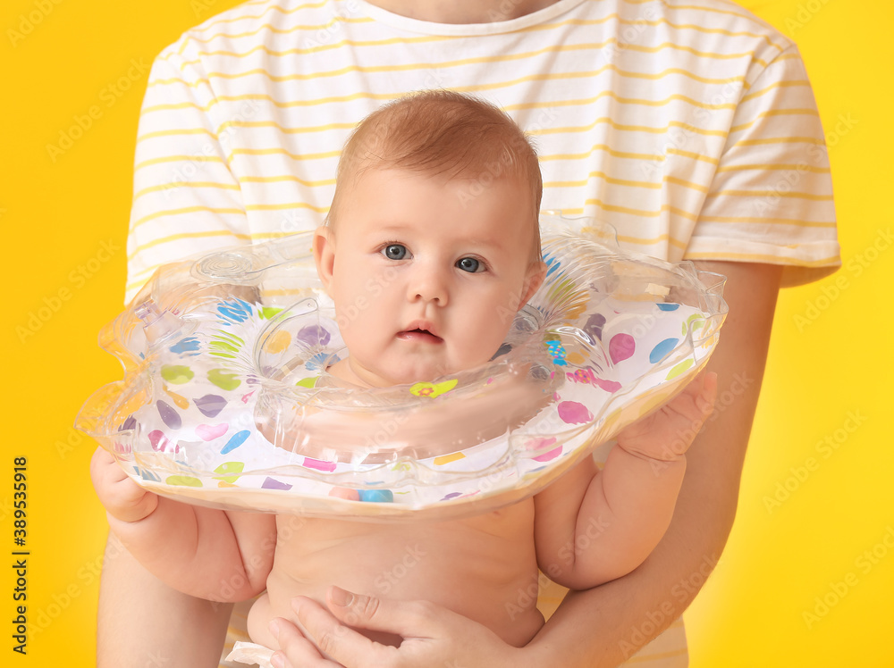 Woman and cute baby with inflatable ring on color background