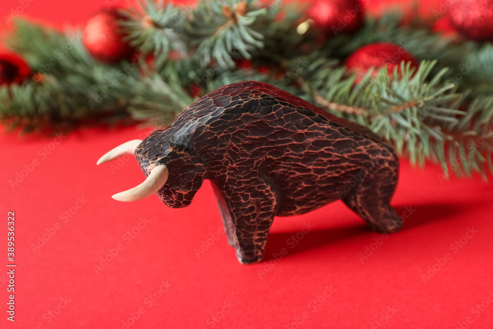 Figurine of bull and New Year decor on color background