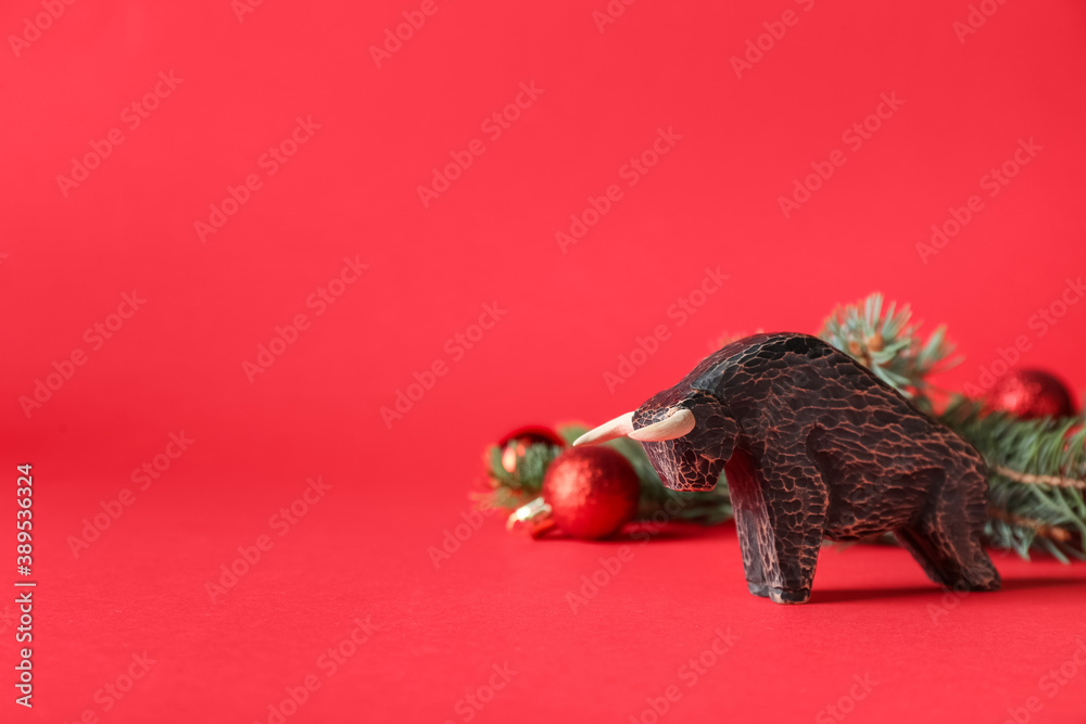 Figurine of bull and New Year decor on color background