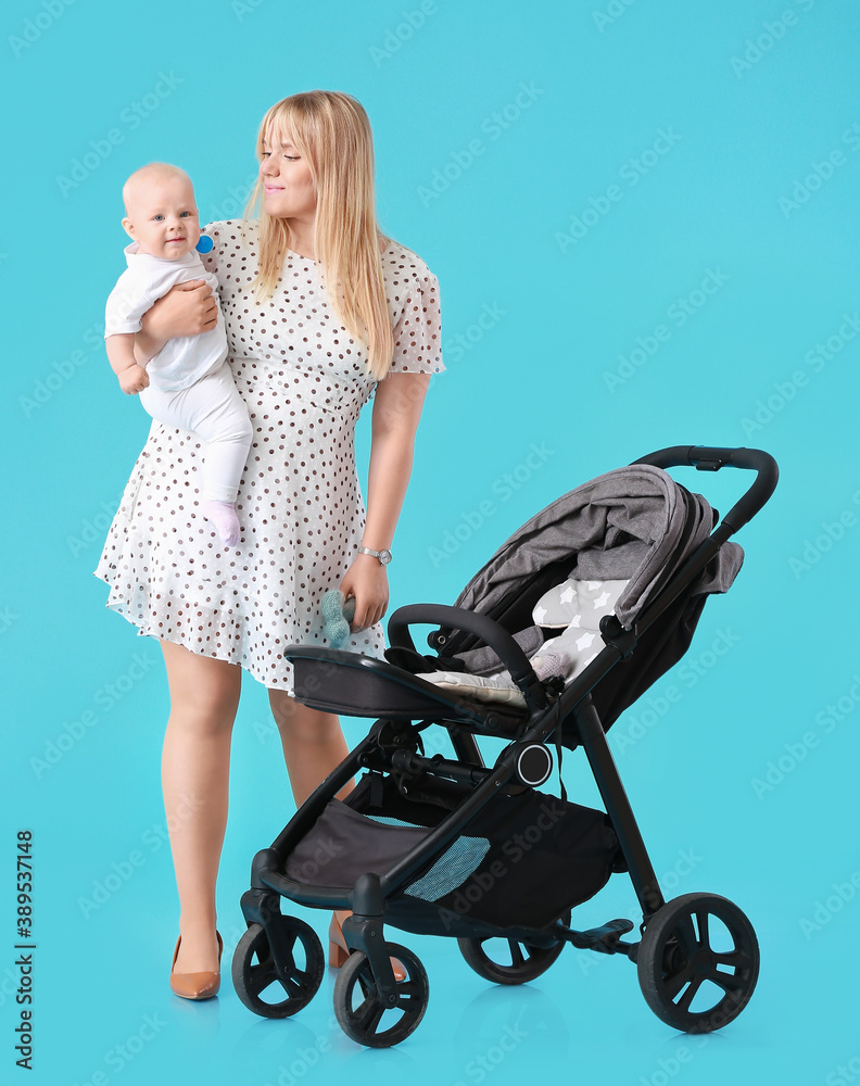 Woman with her cute baby and stroller on color background