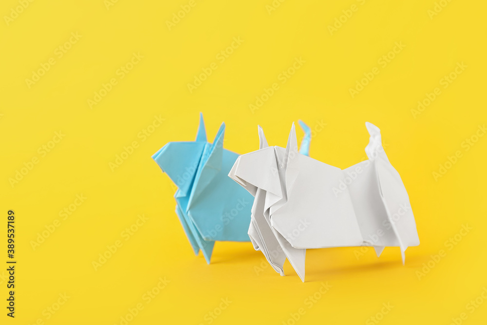 Origami bulls as symbol of year 2021 on color background