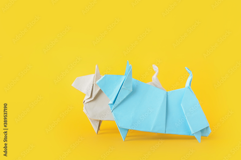 Origami bulls as symbol of year 2021 on color background