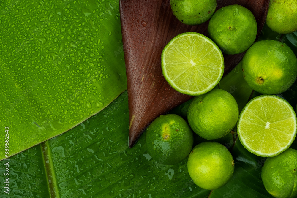 Pile of half and whole fresh lime juicy on green banana leaves with clearly water drop on surface