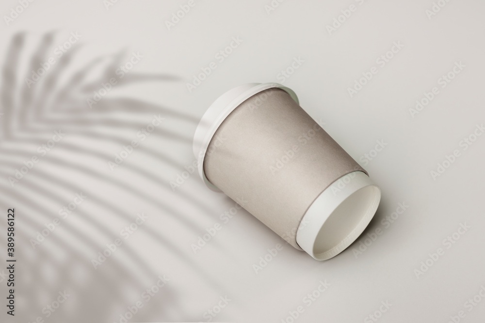 Gray paper cup with palm leaf shadow