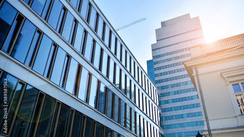 Blue curtain wall made of toned glass and steel constructions under blue sky. A fragment of a buildi