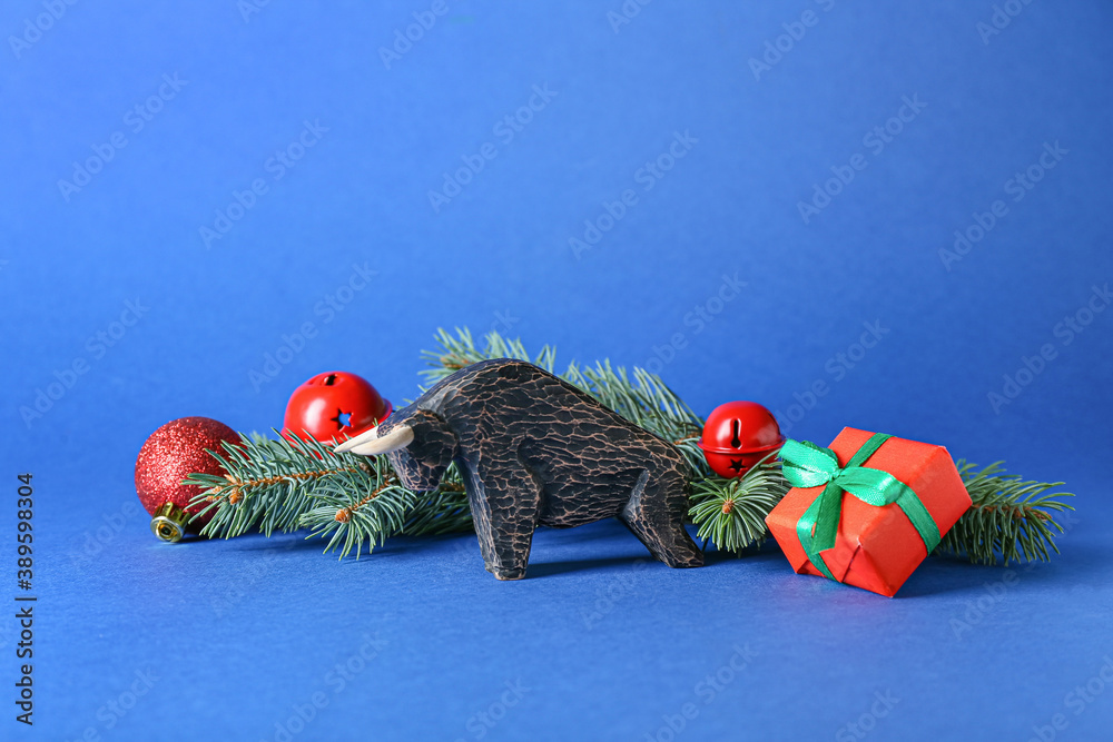 Figurine of bull and New Year decor on color background