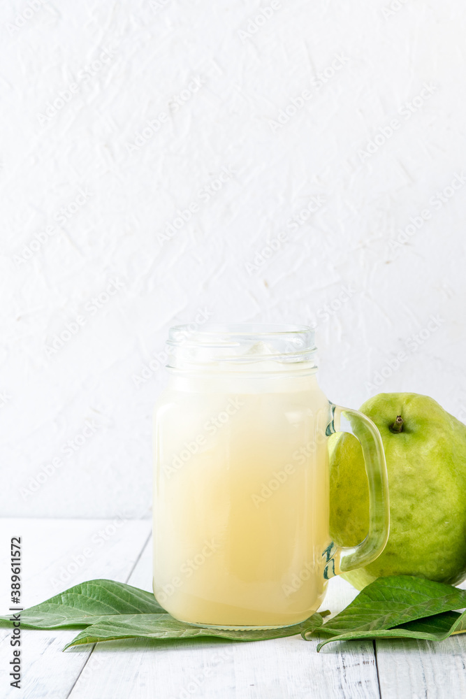 Delicious guava fruit with fresh juice set on white wooden table background.