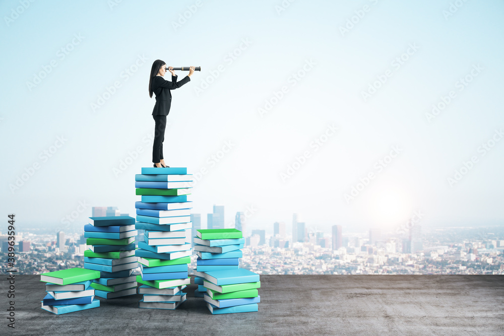 Young businesswoman with binocular standing on color books