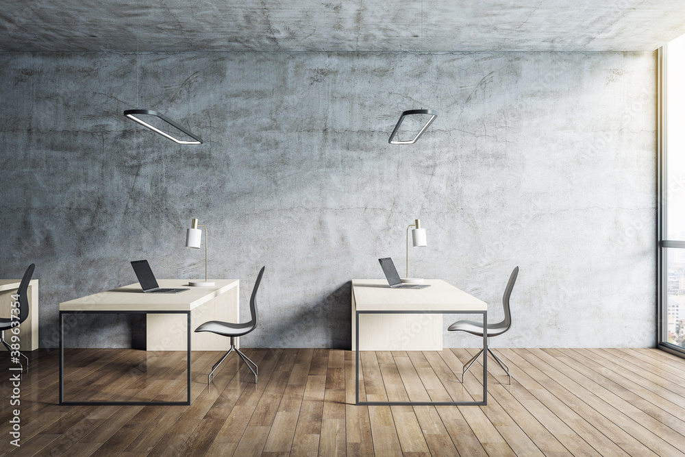 Office desk with laptop and blank concrete wall.