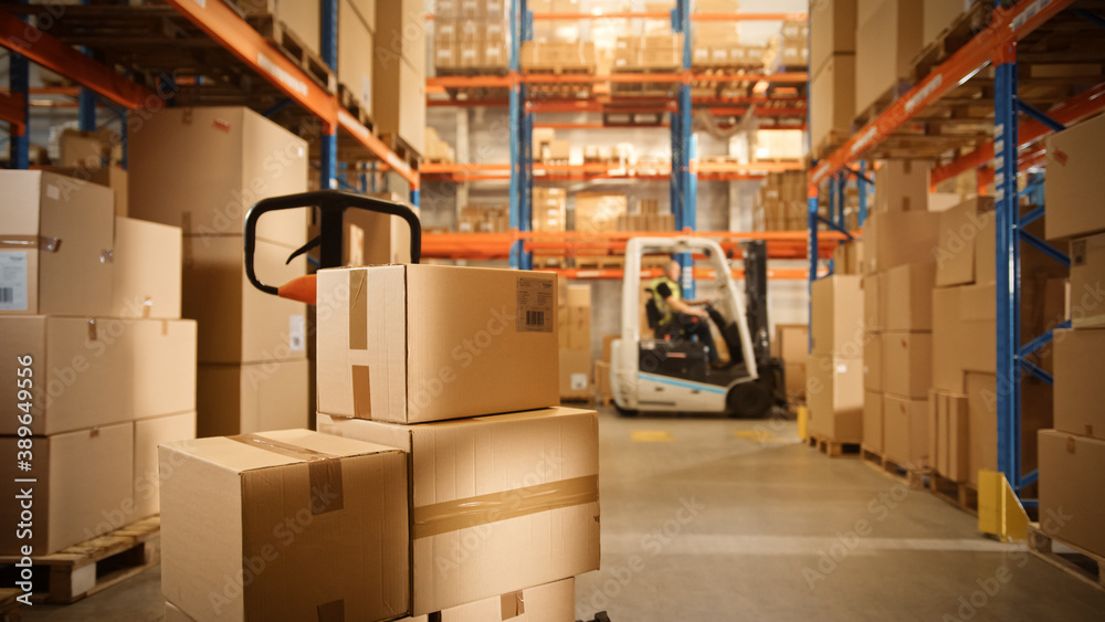 Big Retail Warehouse full of Shelves with Goods Stored on Manual Pallet Truck in Cardboard Boxes and