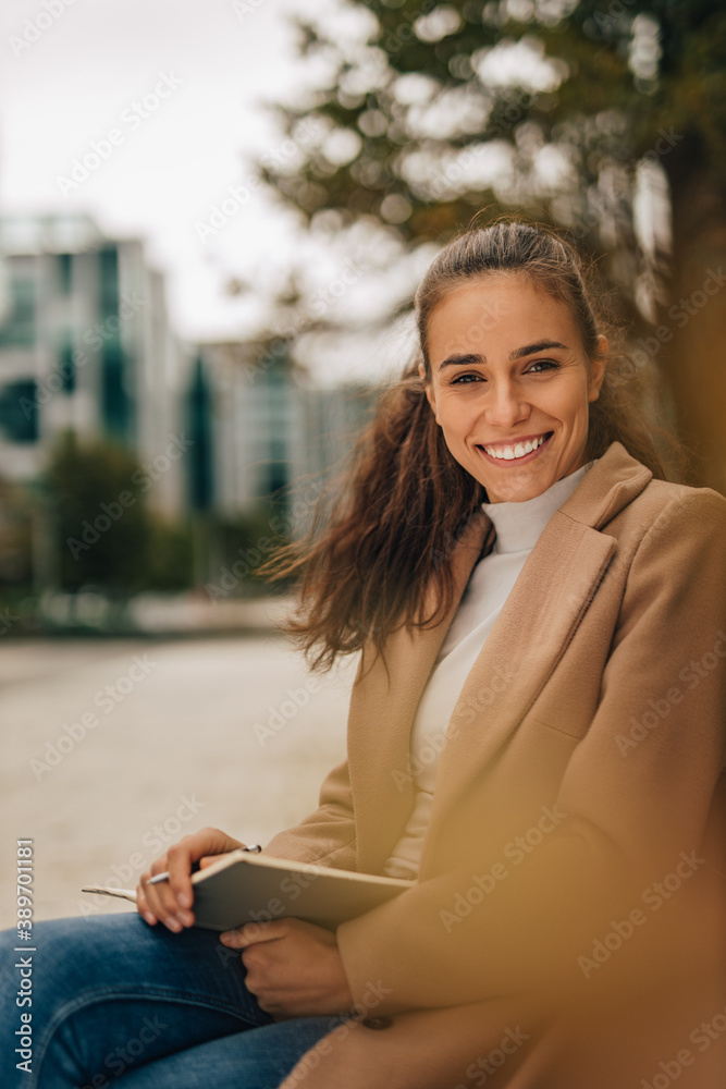 Girl with nice smile,in a trendy fashion clothes, holding notebook.