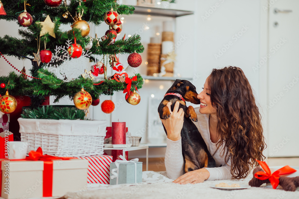 Sweet brunette woman celebrating winter holidays with her pet dog.