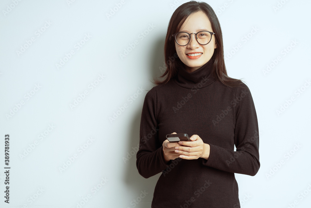 Portrait of a smiling asian businesswoman standing with crossed arms and wearing glasses, holding sm