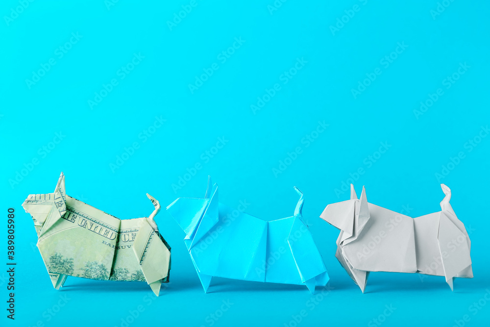 Origami bulls as symbol of year 2021 on color background