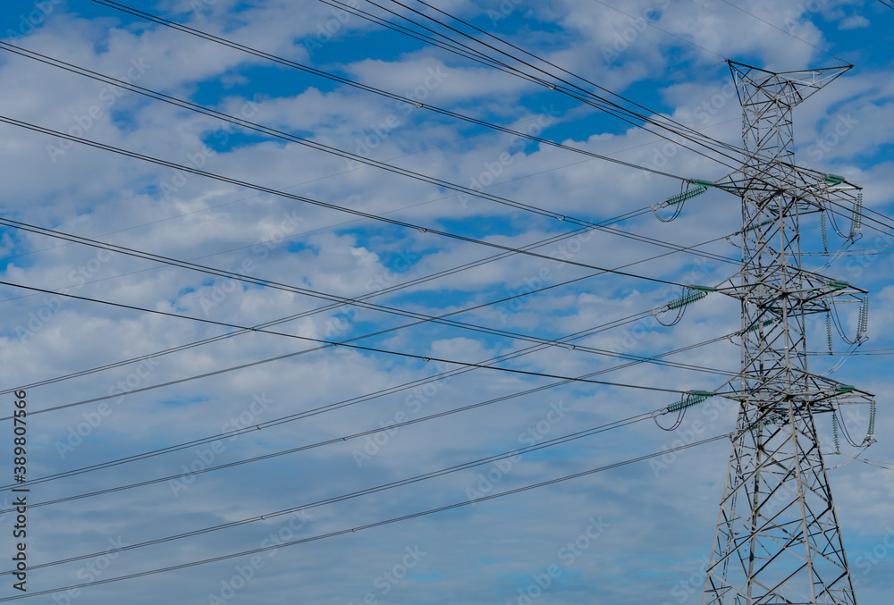 High voltage electric pylon and electrical wire against blue sky and clouds. Bottom view of electric