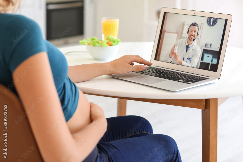 Young pregnant woman video chatting with doctor at home