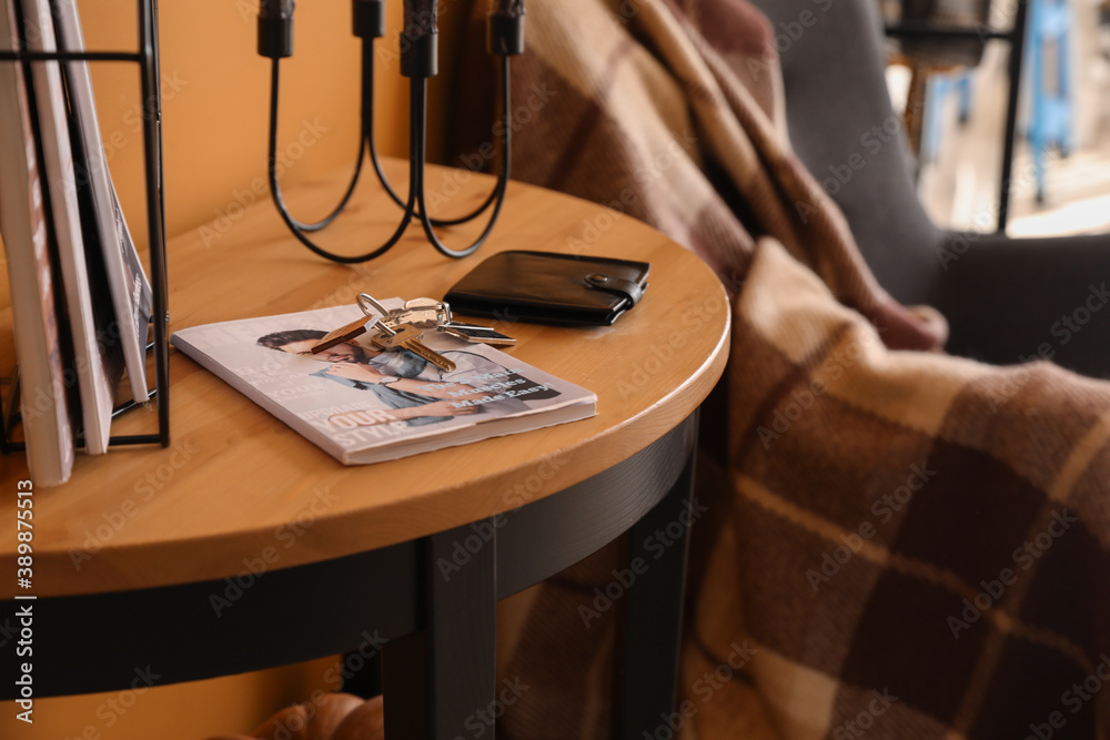 Keys with wallet and fashion magazine on table in hall