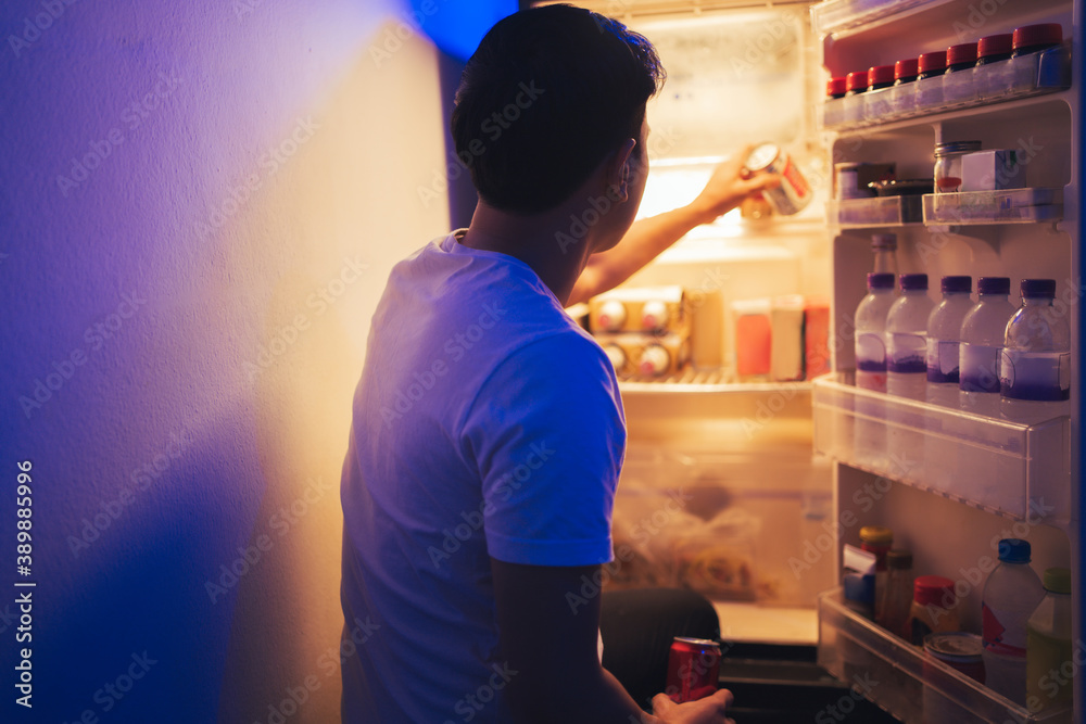 Asian men he is opening the refrigerator.Drank soft drinks during the night