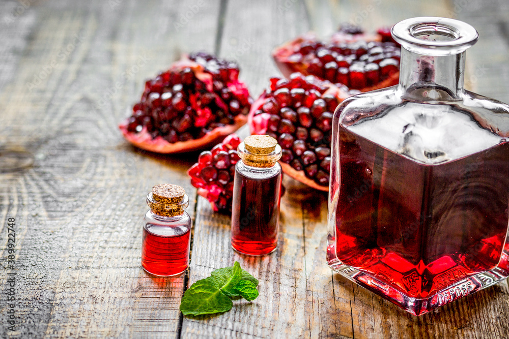 sliced pomegranate and extract in glass on wooden background