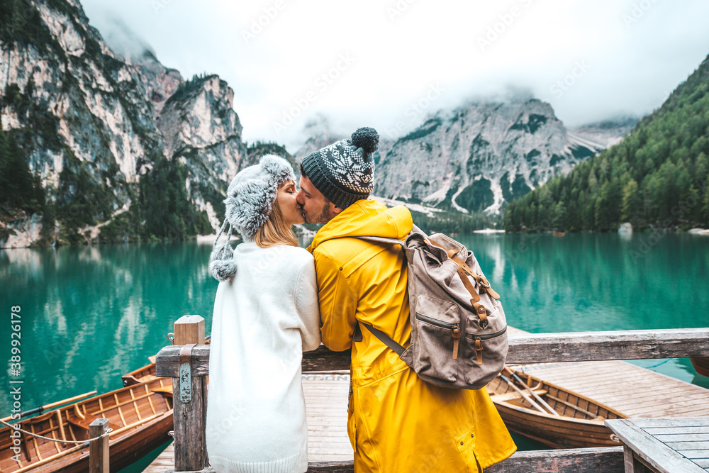 Romantic kiss of a couple of adults visiting an alpine lake at Braies Italy. Tourist in love spendin