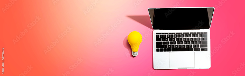 Laptop computer with a yellow light bulb from above