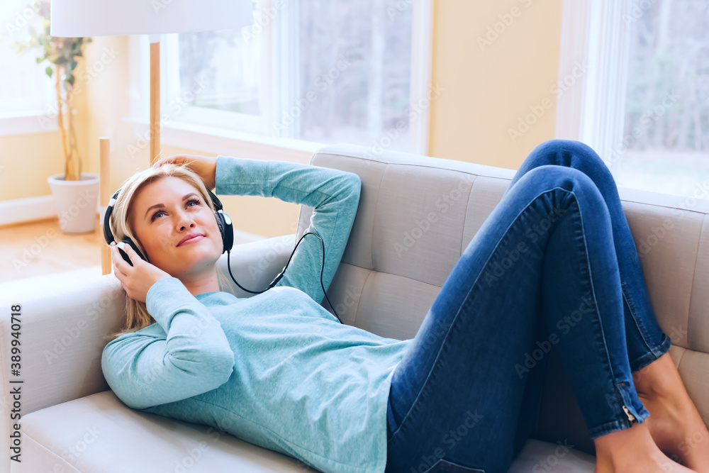 Happy young woman listening to music on headphones at home