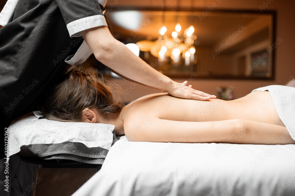 Professional female masseur doing a back massage to a young woman at Spa salon