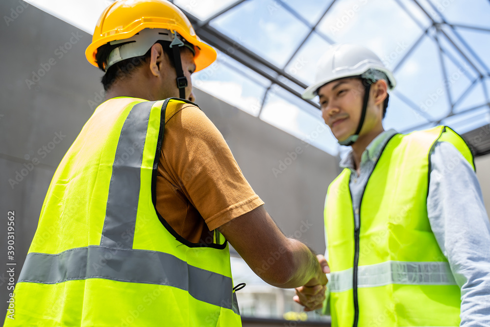 亚洲结构工程师和工人在建筑工地握手。