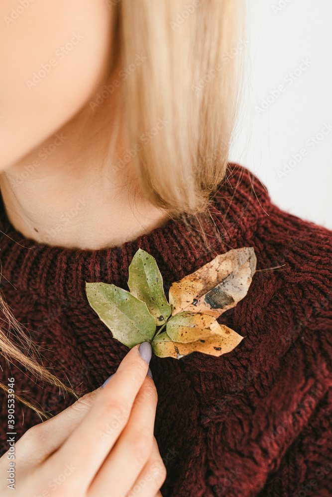 秋天，穿着毛衣的女人拿着清脆的树叶