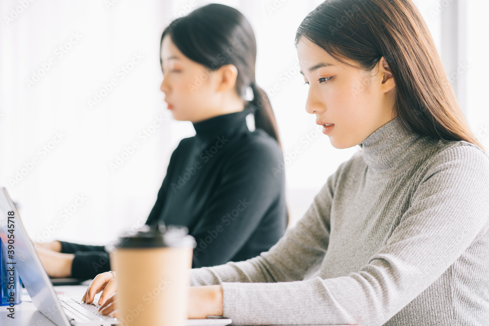 two asian business women are gathered in the office