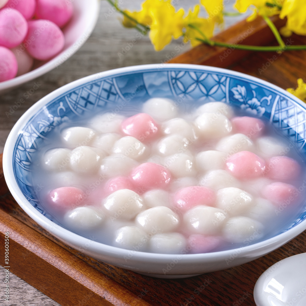 Close up of red and white tangyuan in blue bowl on wooden background for Winter solstice.