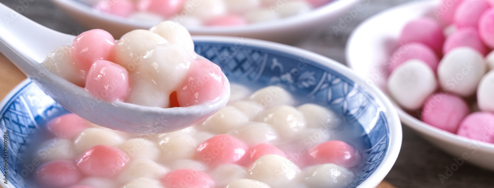 Close up of red and white tangyuan in blue bowl on wooden background for Winter solstice.